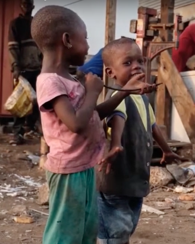 Two children stand in scrap yard